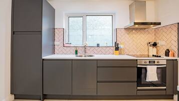 A modern kitchen with a double sink, a built-in oven, and a window above the sink.