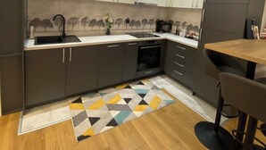 A modern kitchen with dark cabinets, a wooden countertop, and a patterned rug.