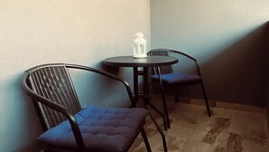 A corner with two black metal chairs with blue cushions and a small round table with a white lantern.