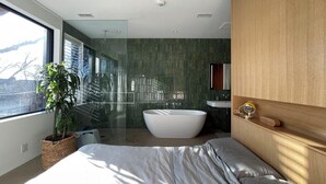 A modern bedroom with a large bed, a bathtub, and a shower area. - Luxury Family Home Near Beaches & Parks | Sleeps 9 | Chef’s Kitchen & Yard (Toronto)