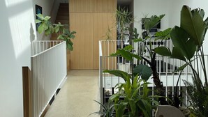 A spacious hallway with a wooden floor, white railing, and potted plants. - Luxury Family Home Near Beaches & Parks | Sleeps 9 | Chef’s Kitchen & Yard (Toronto)