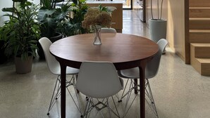 A modern dining area with a wooden table, white chairs, and a hanging light fixture. - Luxury Family Home Near Beaches & Parks | Sleeps 9 | Chef’s Kitchen & Yard (Toronto)