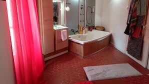 A bathroom with a large bathtub, a mirror, a sink, and a shower.
