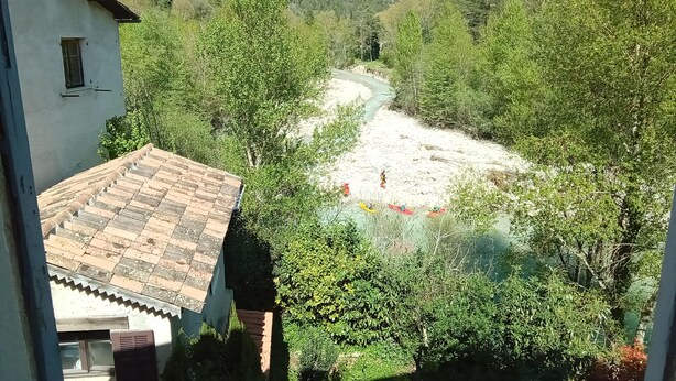 A view of a valley with a river, surrounded by trees and mountains.