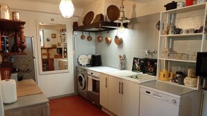 A compact kitchen with a washing machine, a coffee machine, and various kitchen utensils.