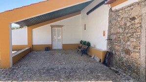Un espacio al aire libre cubierto con un muro de piedra, una banca y una puerta.