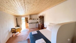 Une chambre à coucher avec un lit, une table de chevet et une vue sur un coin cuisine.