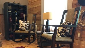 Ein Zimmer mit zwei Schaukelstühlen, einem roten Teppich, einer Holzwand und einem Bücherregal.