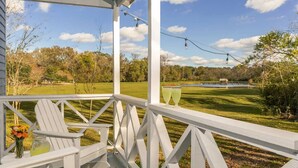 A white wooden deck with a view of a golf course and a pond.