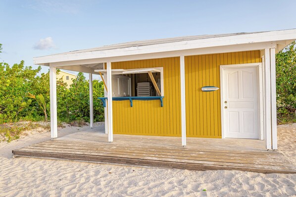 A beach house with a covered porch, a door, and a small outdoor seating area. - Bayview Condo. (Saint John)