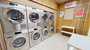 Een wasserette met meerdere wasmachines, een houten wand en instructieborden.