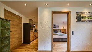 Ein modernes Interieur mit Holzboden, einer Küchenzeile, einem Bett mit Kopfteil und einem Bild an der Wand.