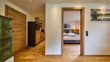 Ein modernes Interieur mit Holzboden, einer Küchenzeile, einem Bett mit Kopfteil und einem Bild an der Wand.