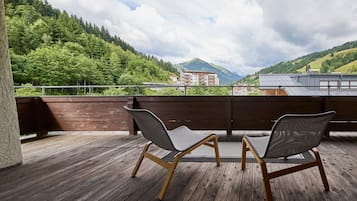 Eine Holzterrasse mit zwei Stühlen, die auf eine Berglandschaft ausgerichtet sind.
