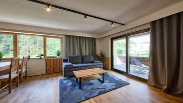 Ein modernes Wohnzimmer mit einer Couch, einem Couchtisch und einem Essbereich mit Holzmöbeln.