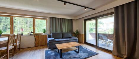 Una sala de estar moderna con un sofá, una mesa de centro y un comedor con muebles de madera.