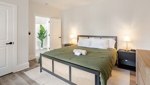 Een slaapkamer met een bed, nachtkastjes, een plafondventilator en een deur.