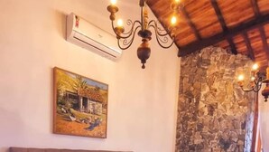 A bedroom with a large bed, a chandelier, a stone wall, and an air conditioning unit. - Fazenda Capuava (Bananal)