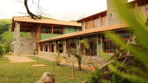 A two-story stone building with a tiled roof, large windows, and a stone pathway leading to the entrance. - Fazenda Capuava (Bananal)