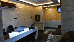 A modern reception area with a marble reception desk, a laptop, and a framed picture on the wall. - GVP Residency (Bengaluru)