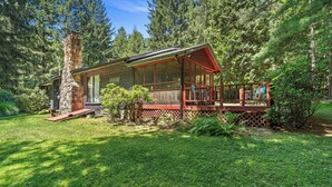 A cabin with a large porch, surrounded by dense forest.