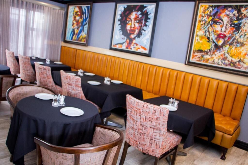 A dining area with round tables, black tablecloths, and patterned chairs.