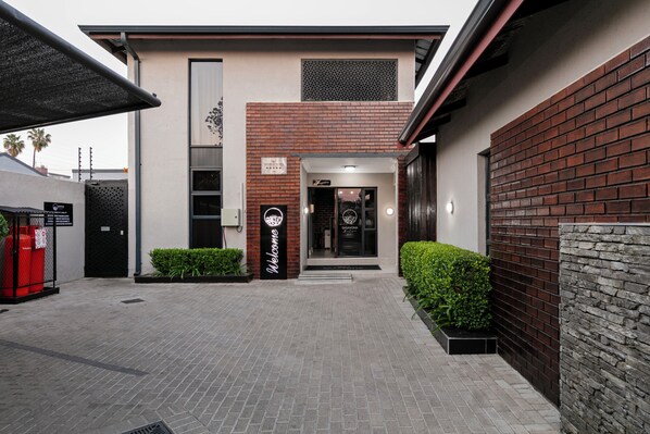 A modern building with a brick facade, a welcome sign, and a well-maintained entrance area. - Sasavona Boutique Hotel (Polokwane)