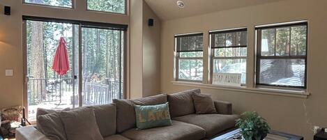 A spacious living room with a large sectional sofa, a glass coffee table, and a ceiling fan.
