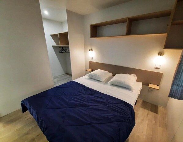 Une chambre d’hôtel moderne dotée d’un grand lit, d’étagères intégrées et de lampes de chevet.