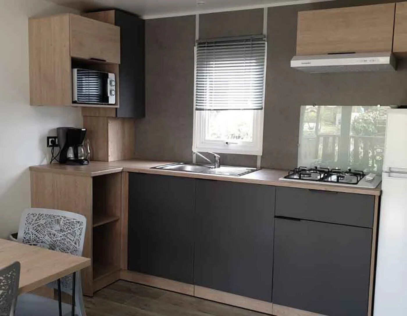A compact kitchen with a sink, stove, and a window with blinds.