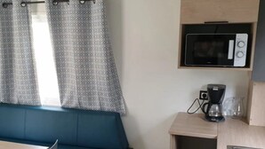 Une petite cuisine équipée d’un four à micro-ondes, d’une machine à café et d’une petite poubelle.
