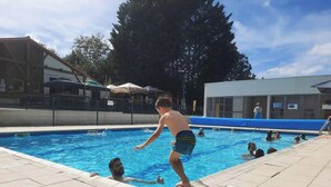 Une piscine où l’on voit des personnes, entourée d’immeubles et d’arbres.