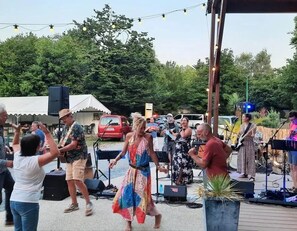 Un groupe de personnes se produisant sur une scène en plein air, avec des instruments de musique et un système de sonorisation.