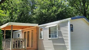 A mobile home with a covered porch and a small deck. - ZEcamping 4 étoiles piscine chauffée mobil-home TV BBQ 36m2 (Secondigny)