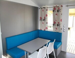 Una habitación moderna con un banco azul, una mesita pequeña y sillas blancas.