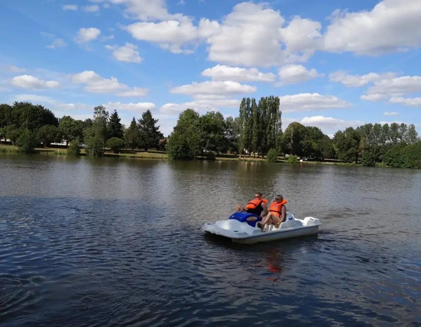 Un lac sur lequel navigue un bateau transportant deux personnes portant des gilets de sauvetage.