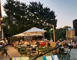 Un espace extérieur aménagé pour les repas, avec des guirlandes lumineuses, des tables et des chaises.