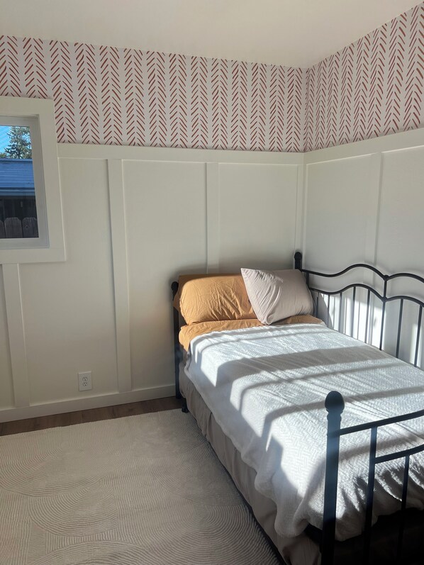 A bedroom with a bed, a window, and patterned wallpaper.