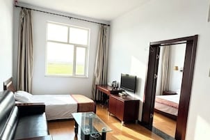 Una habitación de hotel con cama, escritorio, televisor y un amplio ventanal.