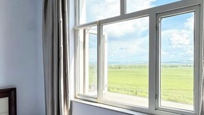 Een uitzicht op een groen veld en een bewolkte lucht.