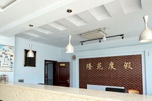 A reception area with a reception desk, pendant lights, a wall with text, and a door.