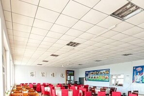 Un comedor amplio con varias mesas y sillas, techo de baldosas y decoración en las paredes.