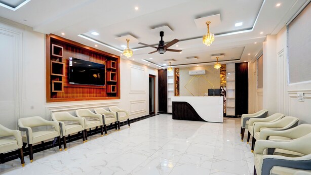 A spacious lobby with a reception desk, seating area, and a large flat-screen TV mounted on the wall. - Aarchh Royale (Noida)