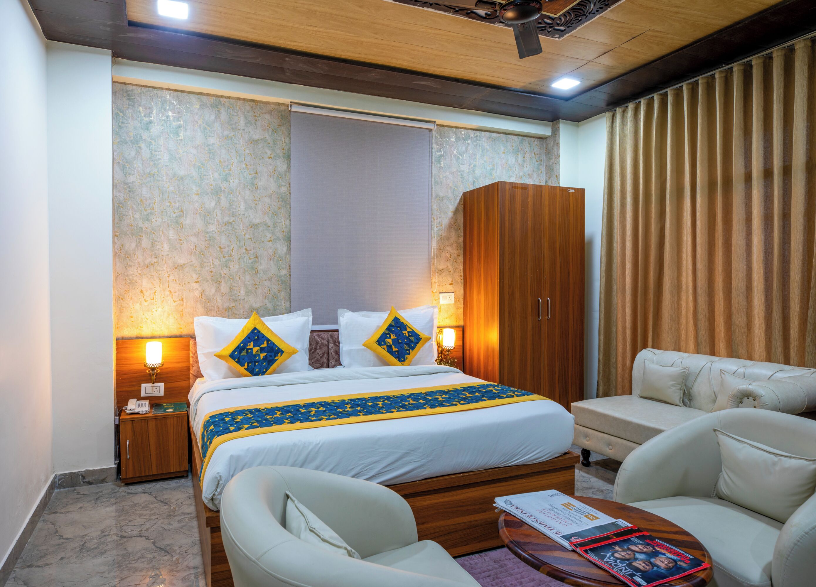 Une chambre d’hôtel équipée d’un lit, de tables de chevet, d’une armoire, d’un canapé et d’un ventilateur de plafond.