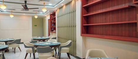 A dining area with round tables, chairs, and ceiling fans.