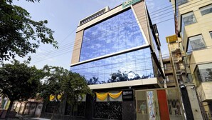 A modern building with a glass facade reflecting the sky. - Aarchh Royale (Noida)