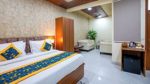 A hotel room with a bed, wardrobe, seating area, and a small kitchenette. - Aarchh Royale (Noida)