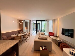 A modern living room with a sofa, dining table, and a flat-screen TV mounted on the wall. - Huswell - Nosso Logies - Chic Stay in Knokke-heist (Knokke-Heist)