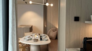 A modern dining area with a round table, wooden chairs, a hanging light fixture, and a built-in bench with a cushion. - Huswell - Nosso Logies - Chic Stay in Knokke-heist (Knokke-Heist)