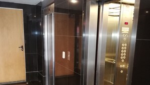 Un ascensor moderno con pantalla digital, panel de control con botones e interior metálico.